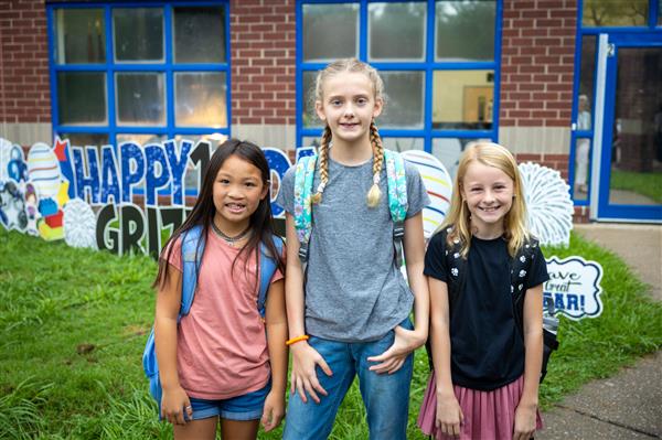 three students smiling in front of WGES